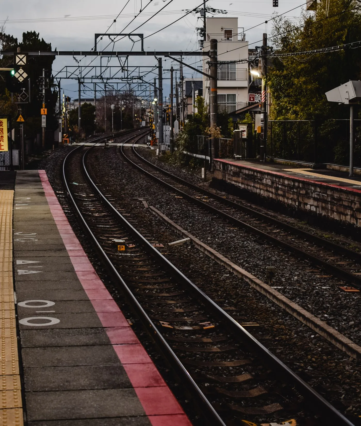 カーブして伸びる線路と、日本の駅のホームの端