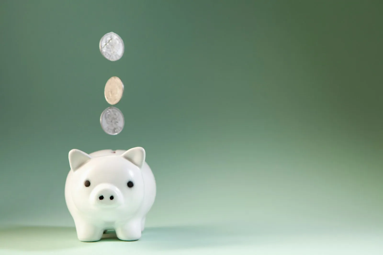 硬貨が落ちていく白い貯金箱