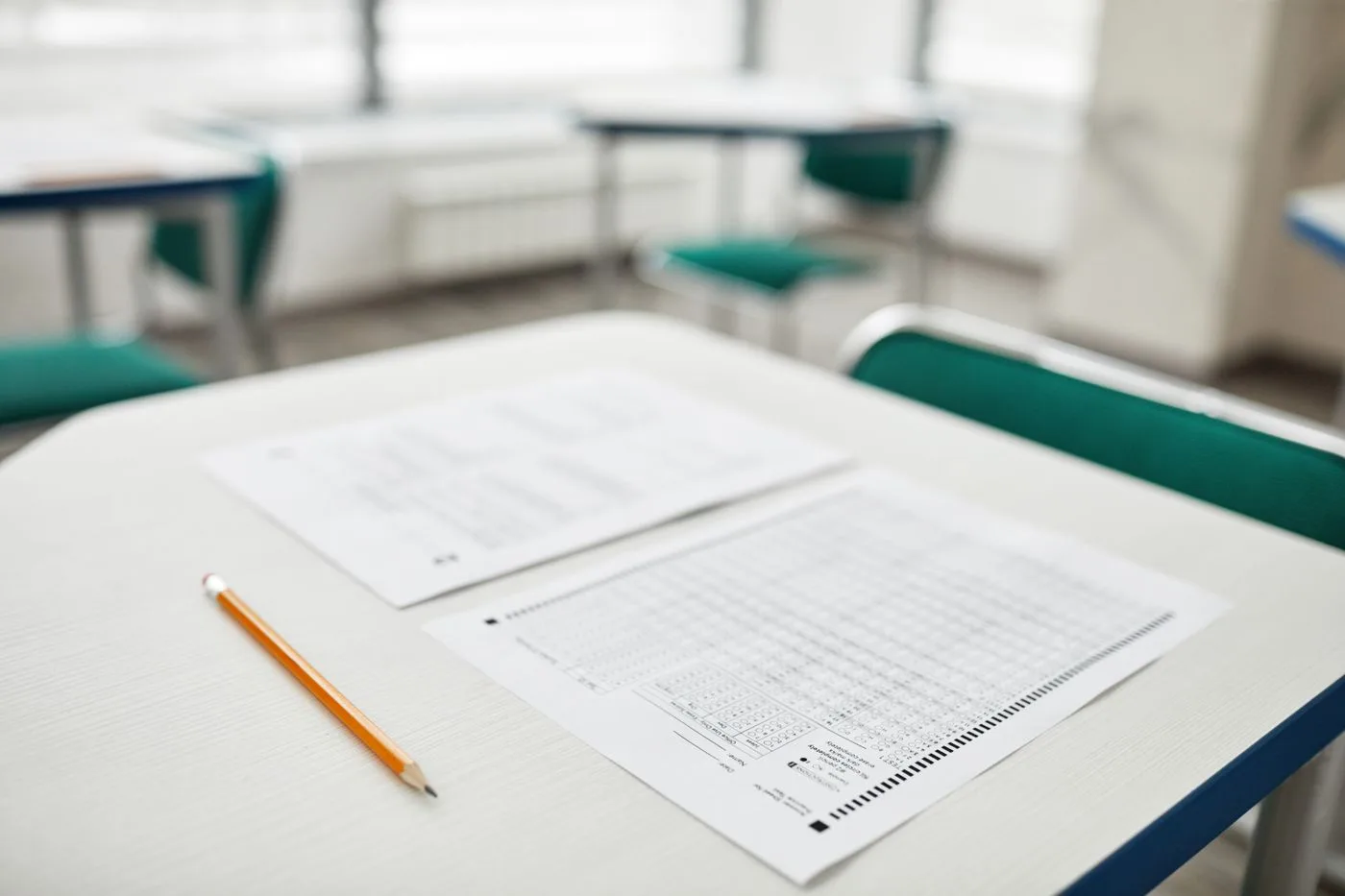 教室の机に置かれたマークシート式の解答用紙と問題用紙、鉛筆